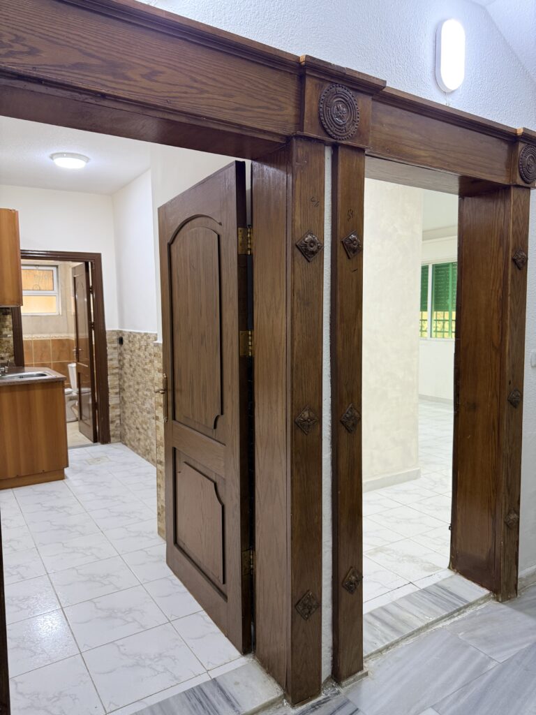 Hallway interior of Apartment D-101 with wooden doors and tiled flooring